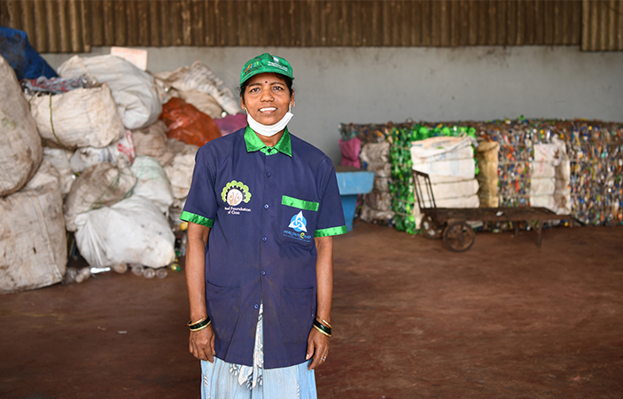 A person stood in a uniform surrounded by large bags of recycled goods.