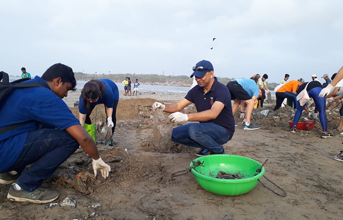 A group of people cleaning up and collecting waste along a waterbed.