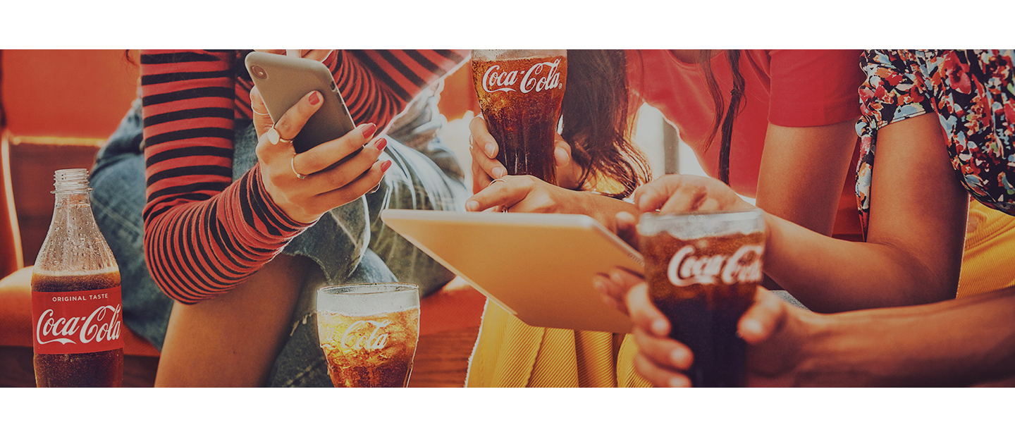 Hands and arms holding bottles of Coca Cola