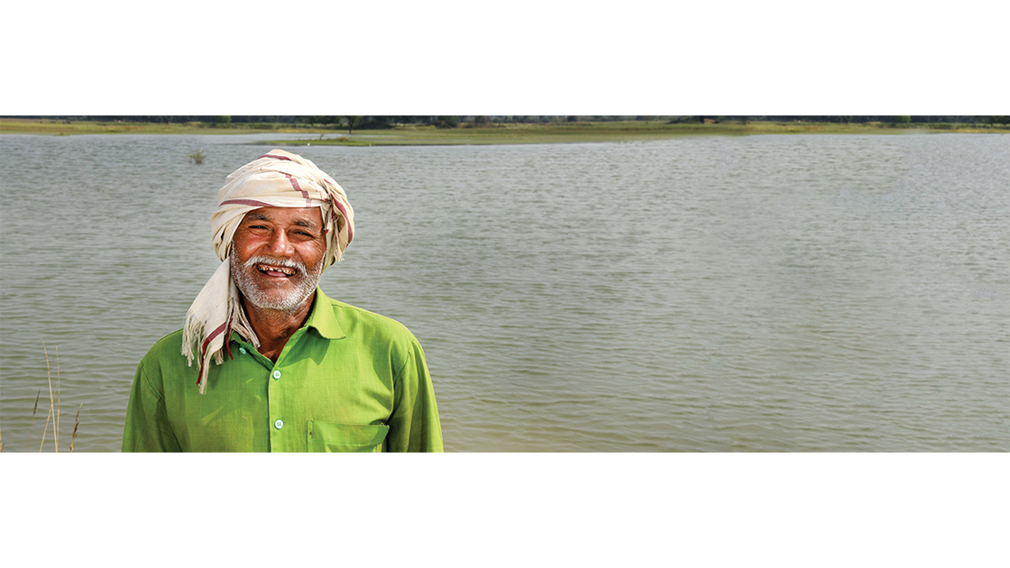 A smiling man in a green shirt, with a river in the background
