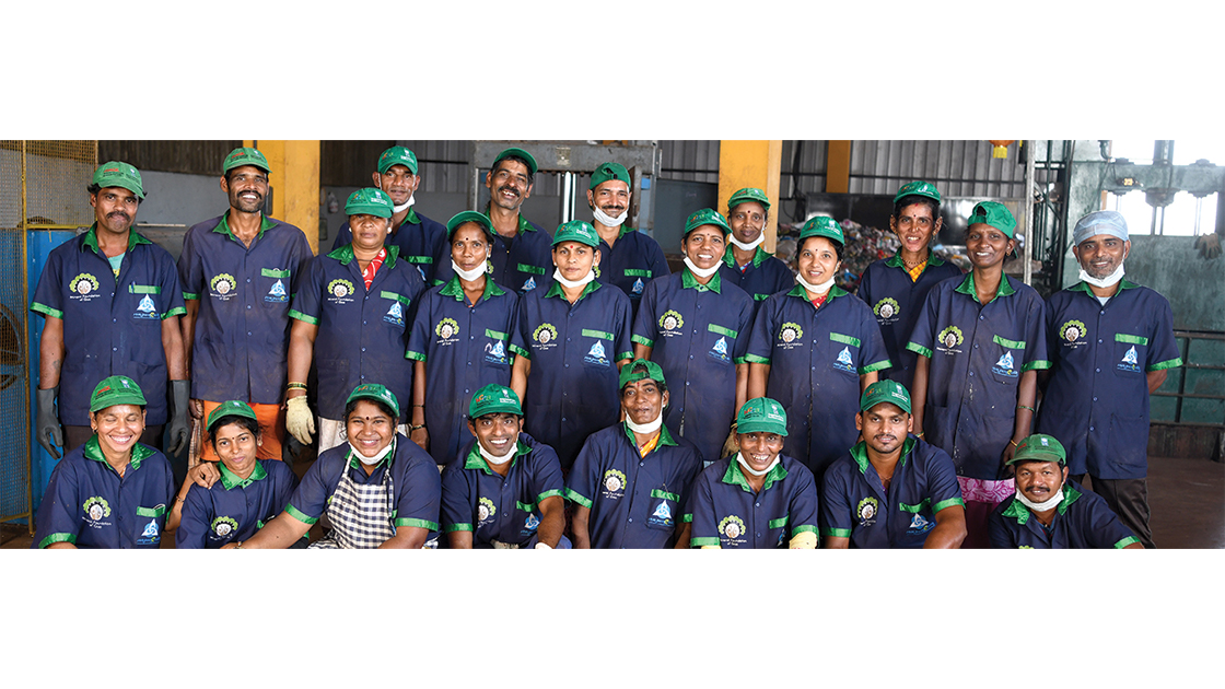A group of people in blue and green uniforms stood smiling.