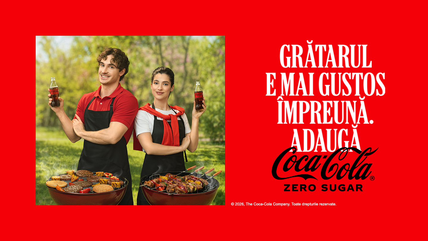 Cuplu pregătind masa de Paște în bucătărie, cu ouă colorate, mâncare tradițională și o sticlă de Coca-Cola Zero Sugar