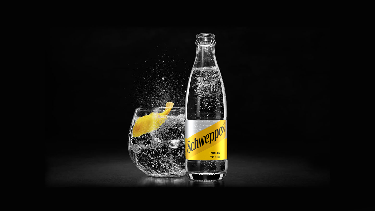 Doza de Schweppes, cu inscripția Born Social, cu un cadru de petrecere pe fundal