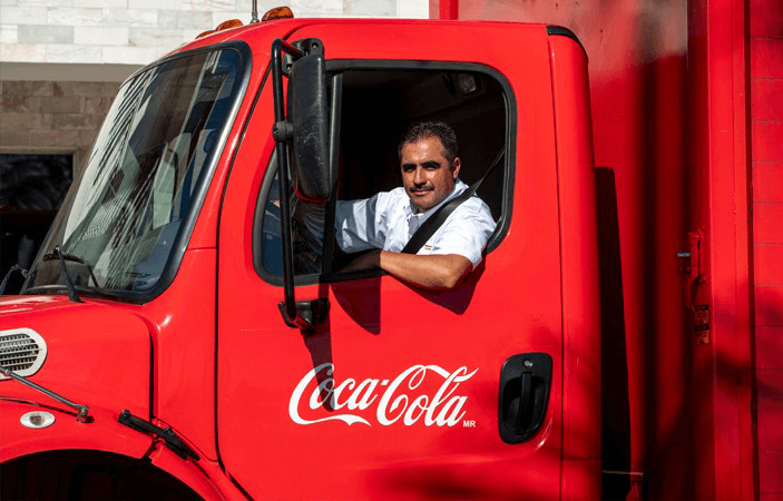 Conductor mira a cámara, en su camión de Coca-Cola