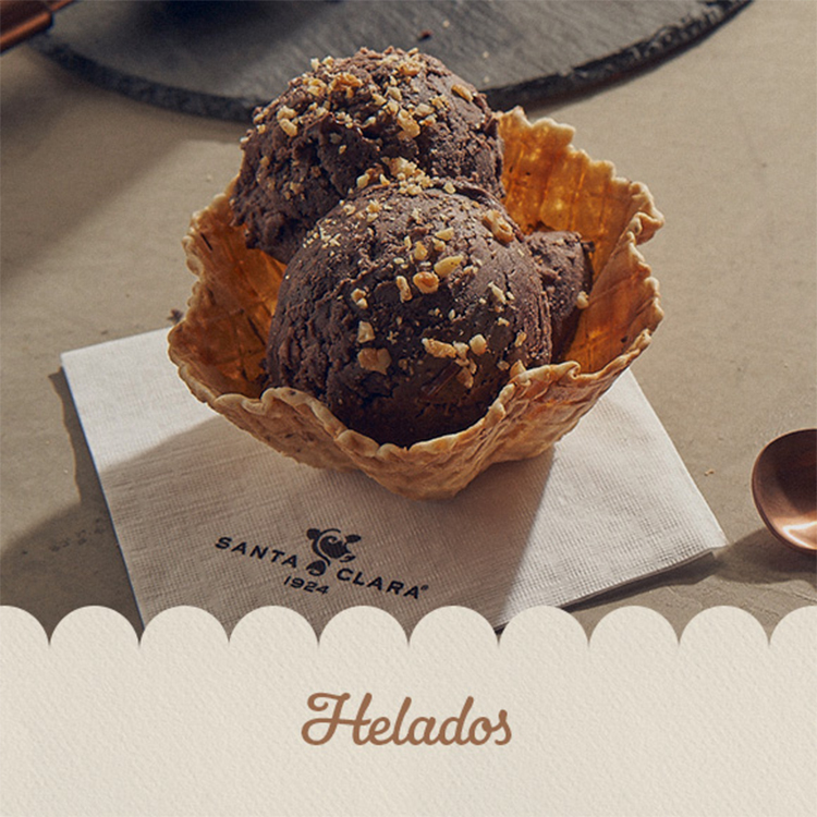 Helado de chocolate en bola servido en un cono tipo tulipán, espolvoreado con nueces, sobre una servilleta con el logo de Santa Clara.