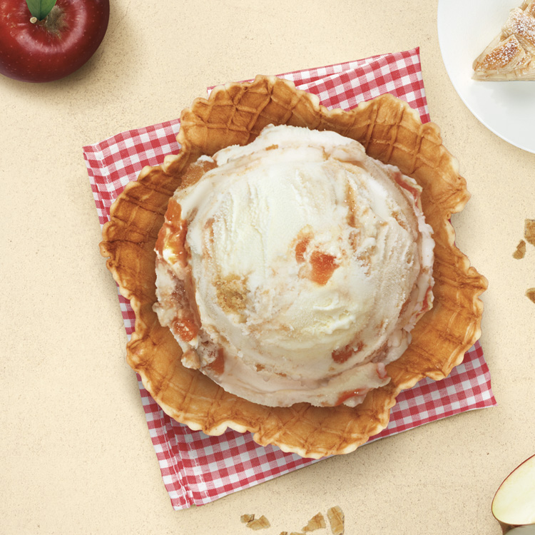 Helado de strudel de manzana de Santa Clara Mexico en una cesta de barquillo, con manzanas rojas y migas de strudel de fondo.