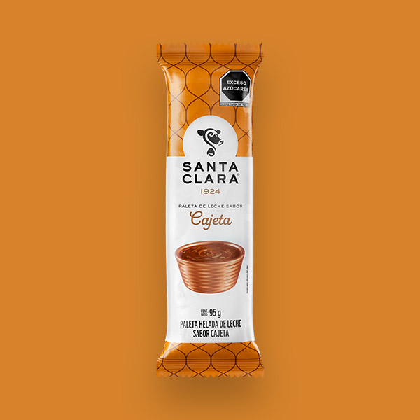 Paleta de leche sabor Cajeta Santa Clara en su empaque con el color característico de la cajeta y con una imagen de cajeta en un recipiente