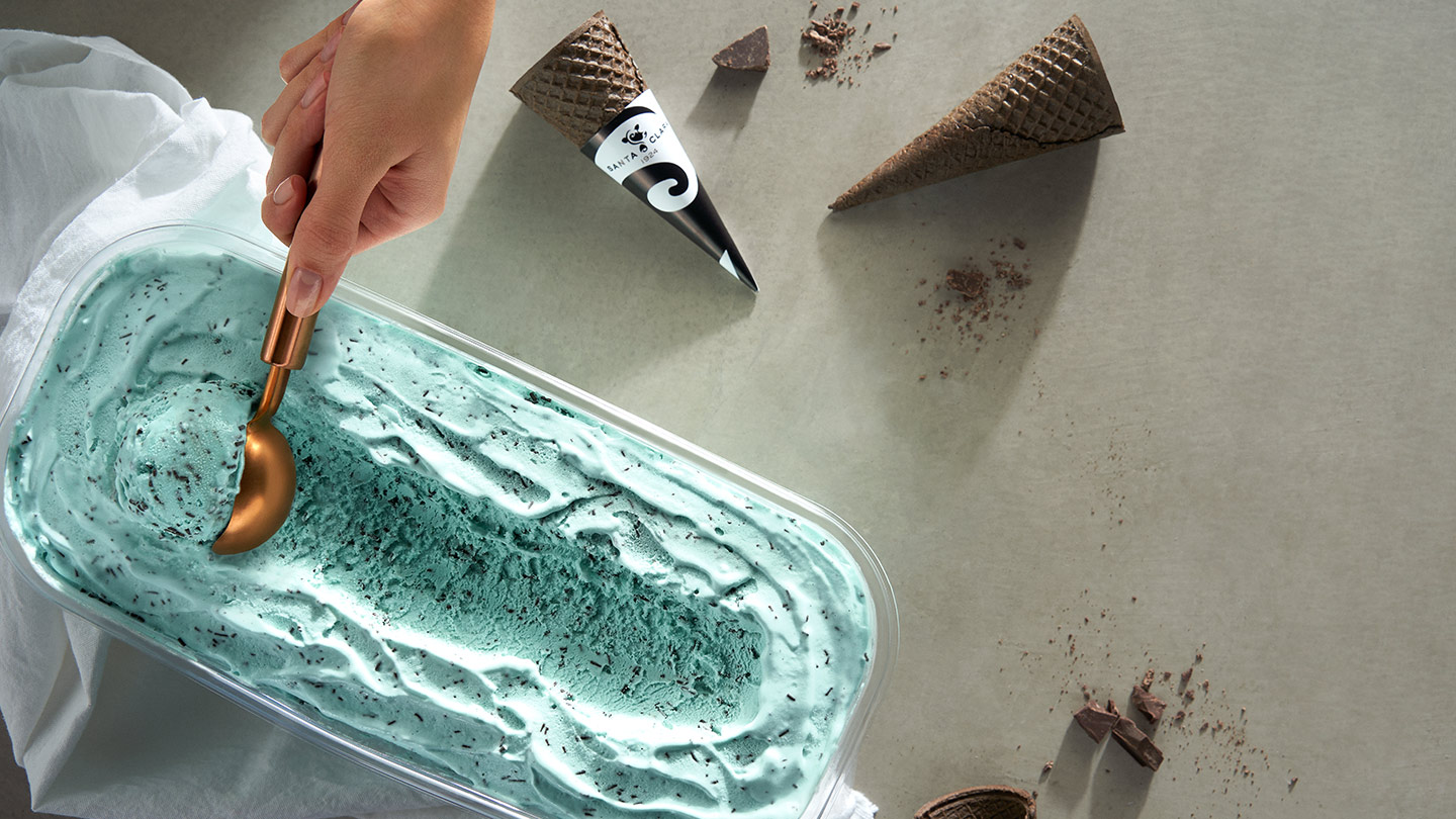 Helado de menta con chispas de chocolate, una mano lo sirve. Cono y chocolate a un lado. Botón: Registrarme.