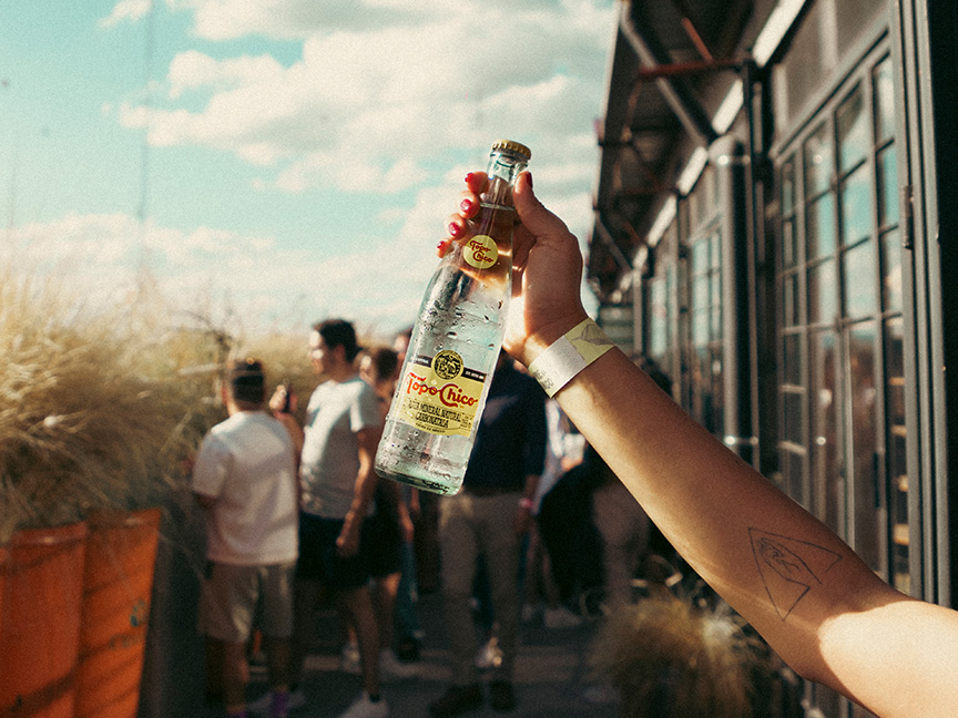 Botella de Topo Chico agua, con plato de comida y hielera Topo Chico.