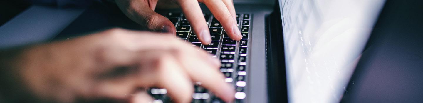 Manos escribiendo en un teclado de computadora