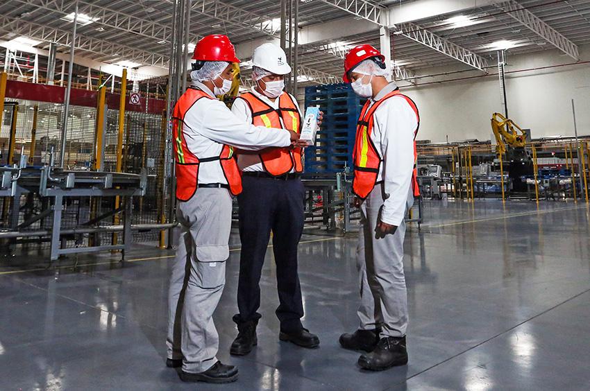 Hombres trabajadores de una fábrica conversan entre sí