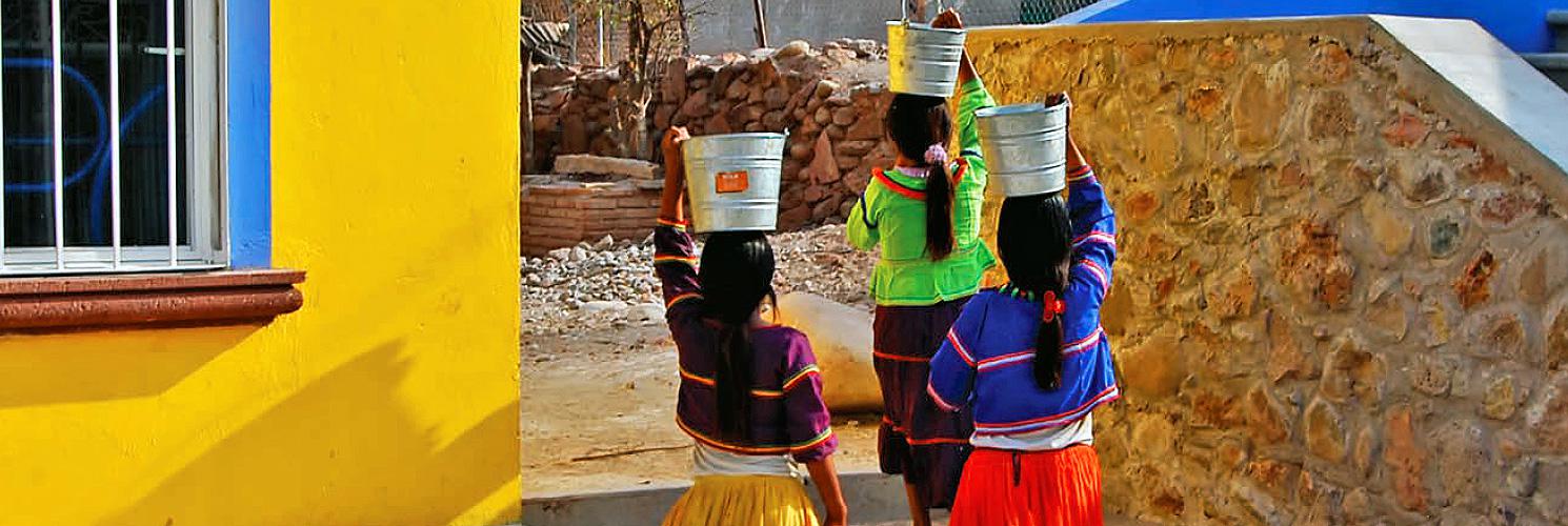 Tres mujeres cargan con baldes de agua