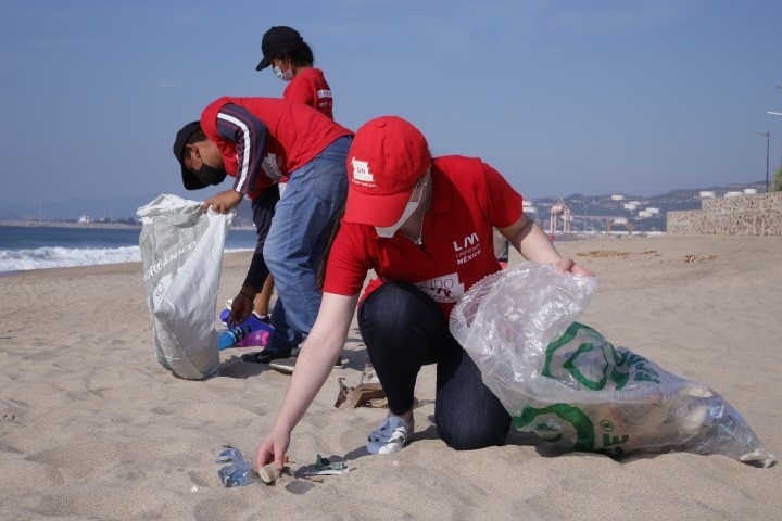 Tres personas recogiendo residuos en una playa
