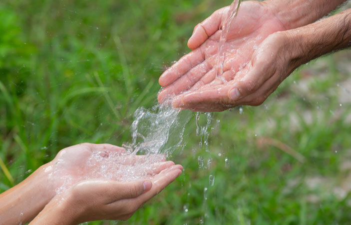 El agua fluye sobre las manos de dos personas