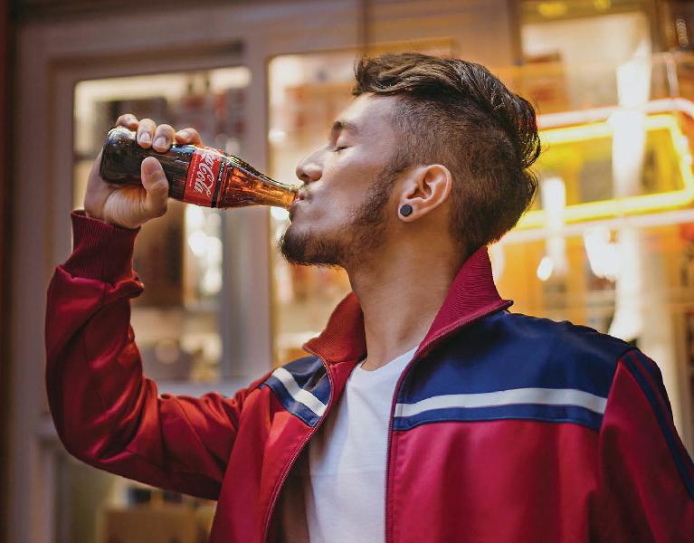 Seorang lelaki sedang menyeruput Coca-Cola Zero Sugar