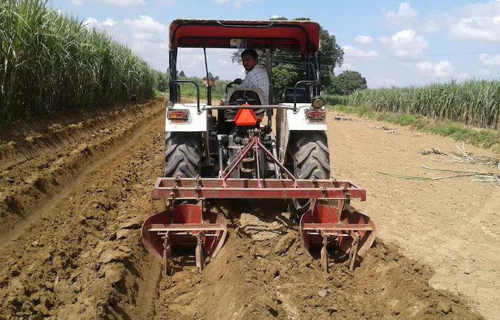 Sebuah traktor sedang meratakan ladang di persekitaran pertanian