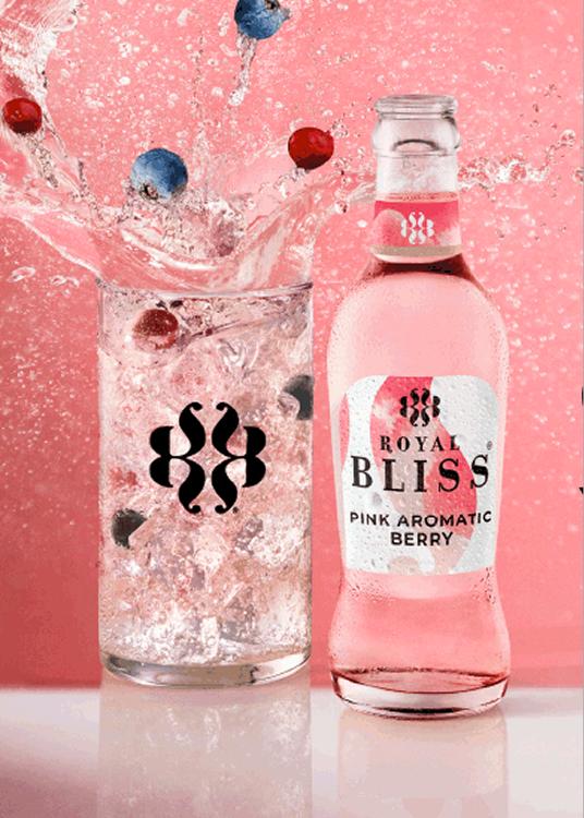 Twee flessen drank naast elkaar tegen een roze achtergrond: een heldere sprankelende drank met fruit en een roze Bliss-drank