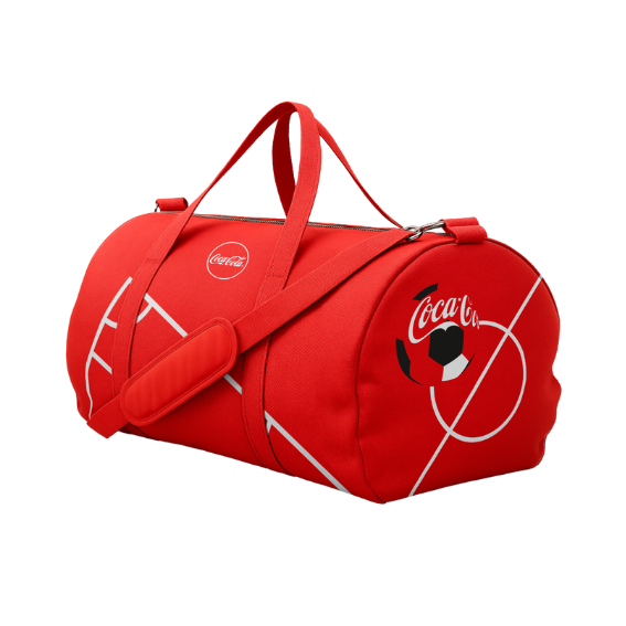 Rode sporttas met het Coca‑Cola‑logo en een wit voetbalveld‑ontwerp, voorzien van handvatten en een verstelbare schouderband, op een witte achtergrond.