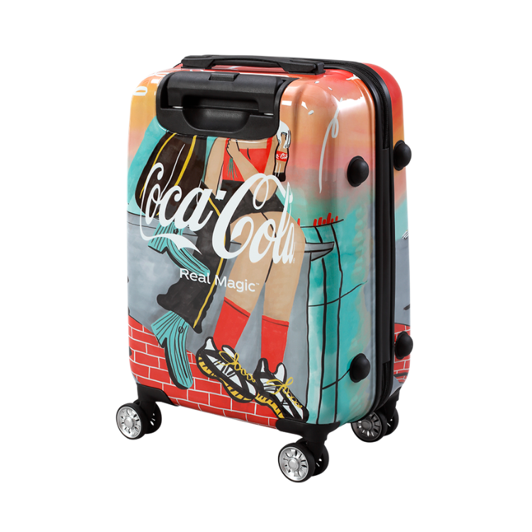 Kleurrijke harde Coca-Cola koffer op vier wielen met artistieke illustratie van benen, sneakers en het Coca-Cola-logo op de voorkant.