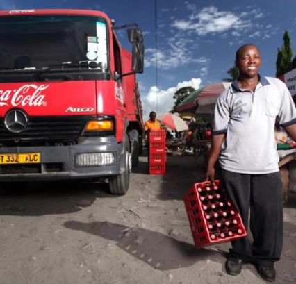 Een mannelijke arbeider die een krat Coca-Cola tilt