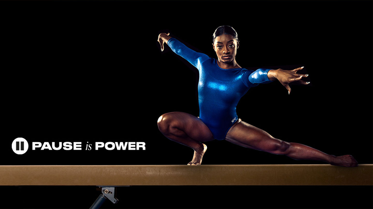 En kvinnelig atlet i en halvveis sittende stilling iført en blå gymdrakt