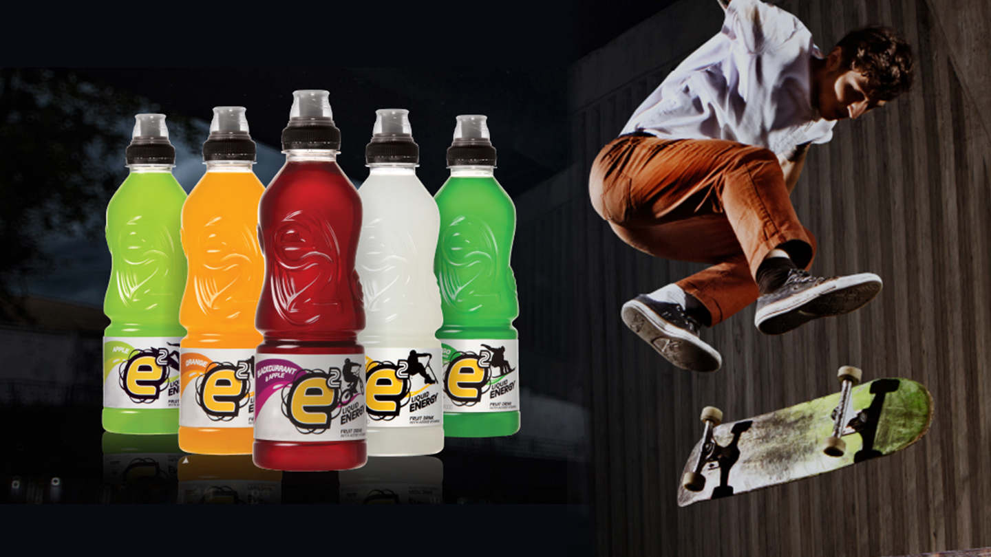 Pack of five E2 bottles next to a skateboarder doing a trick in the air
