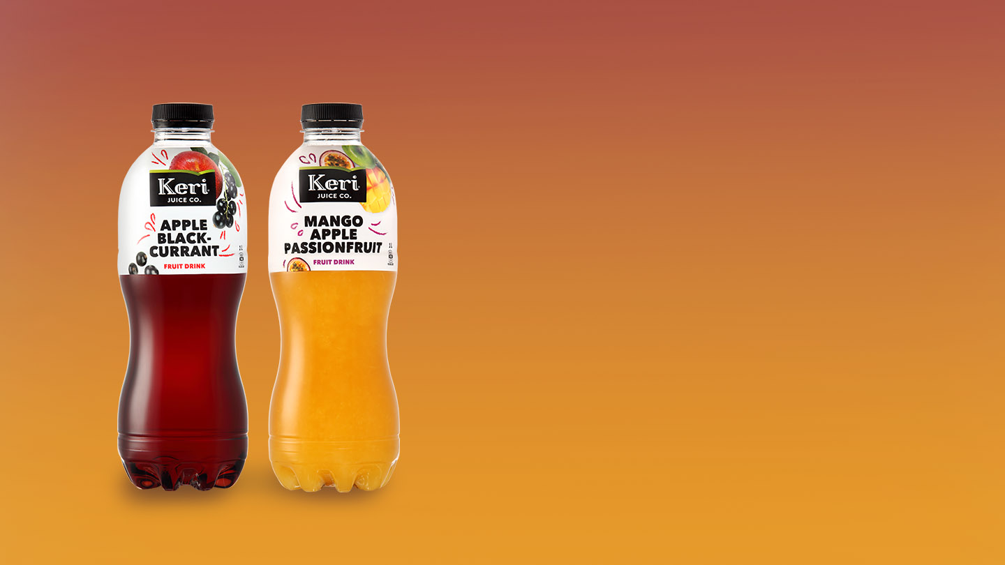 A Keri Premium Orange Juice bottle and on a wooden table with a fork, a knife, and a plate on the left