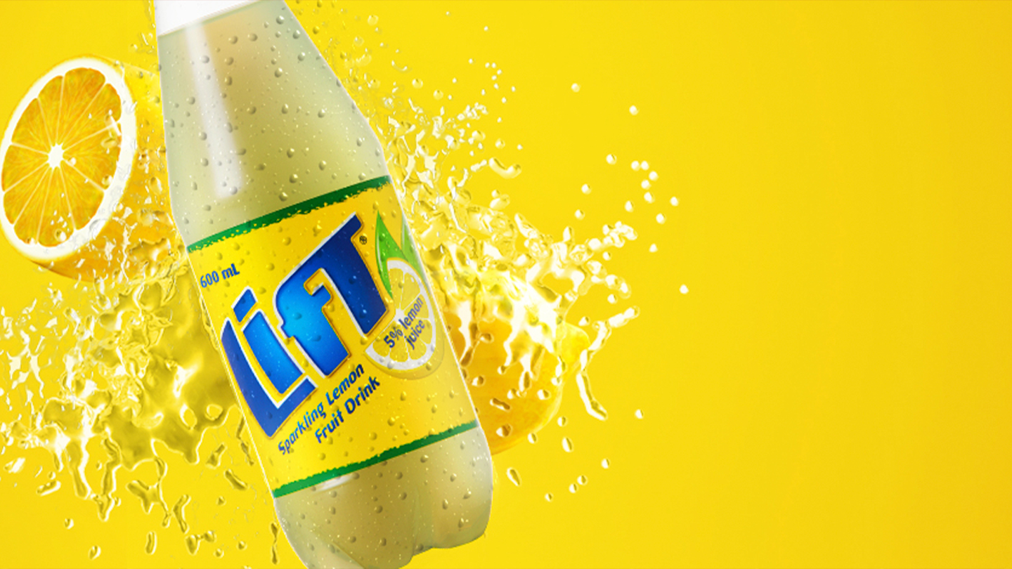 Lift bottle in front of lemon pieces on yellow background
