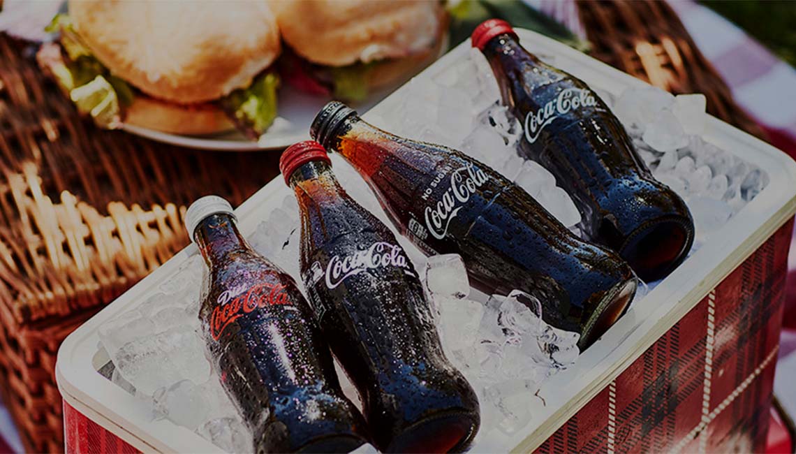 A container full of ice with four bottles of Coca-Cola