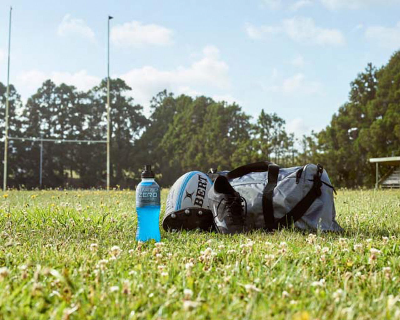 A bottle of Powerade on the ground of an empty rugby field