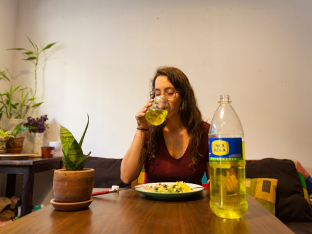 Chica bebiendo Inca Kola en una mesa