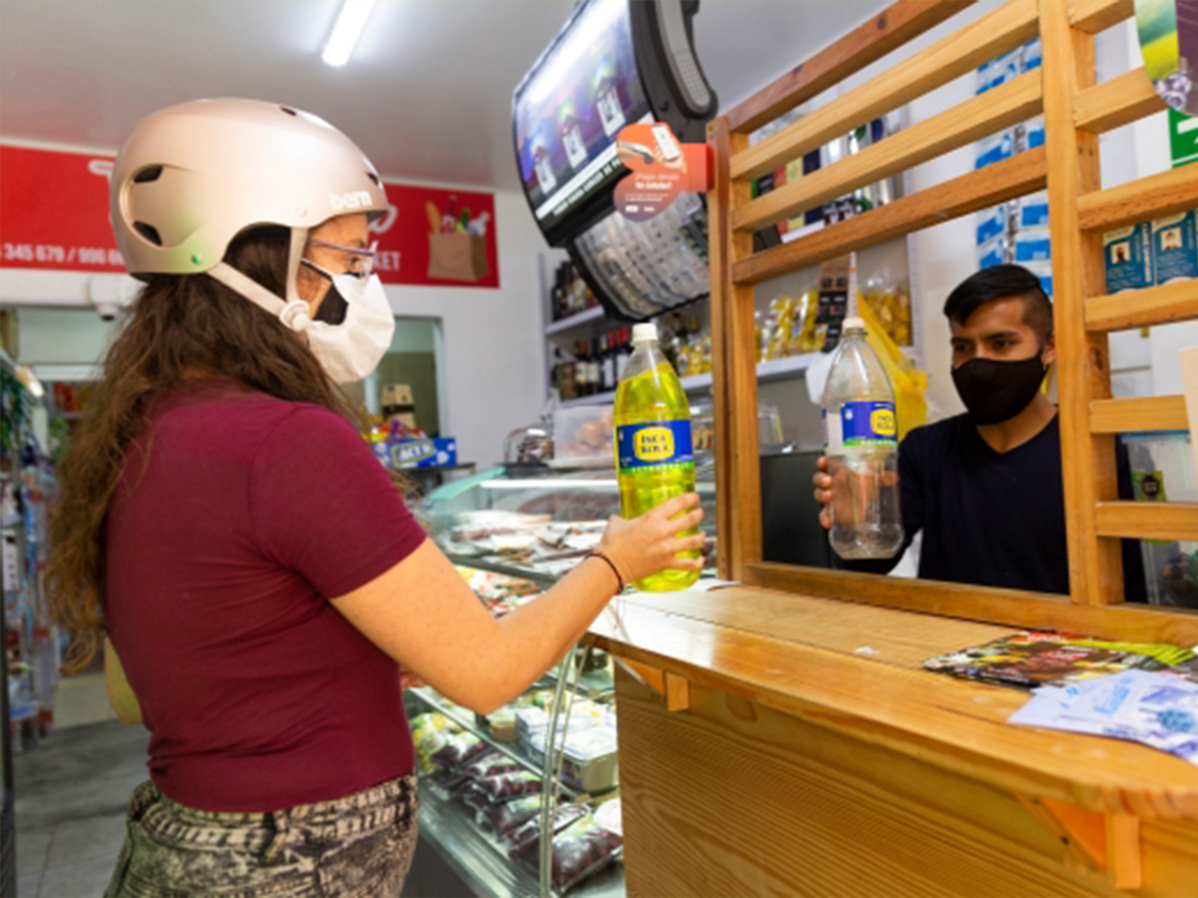 Chica con casco entrega una botella a un vendedor