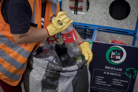 Persona metiendo botella vacía de plástico en una bolsa