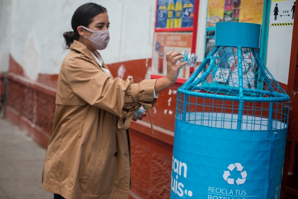 Mujer desechando botella en punto limpio