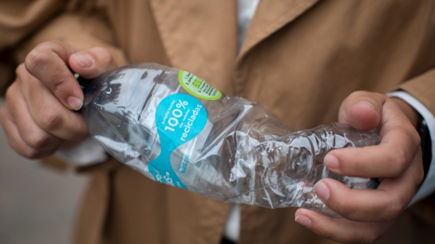 Las manos de una persona aplastando una botella de plástico