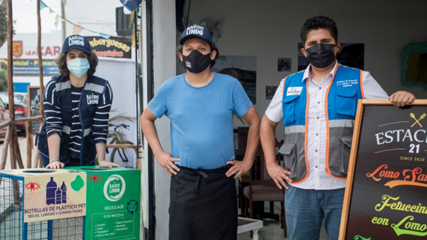 Tres personas con mascarilla posan en la entrada de un restaurante