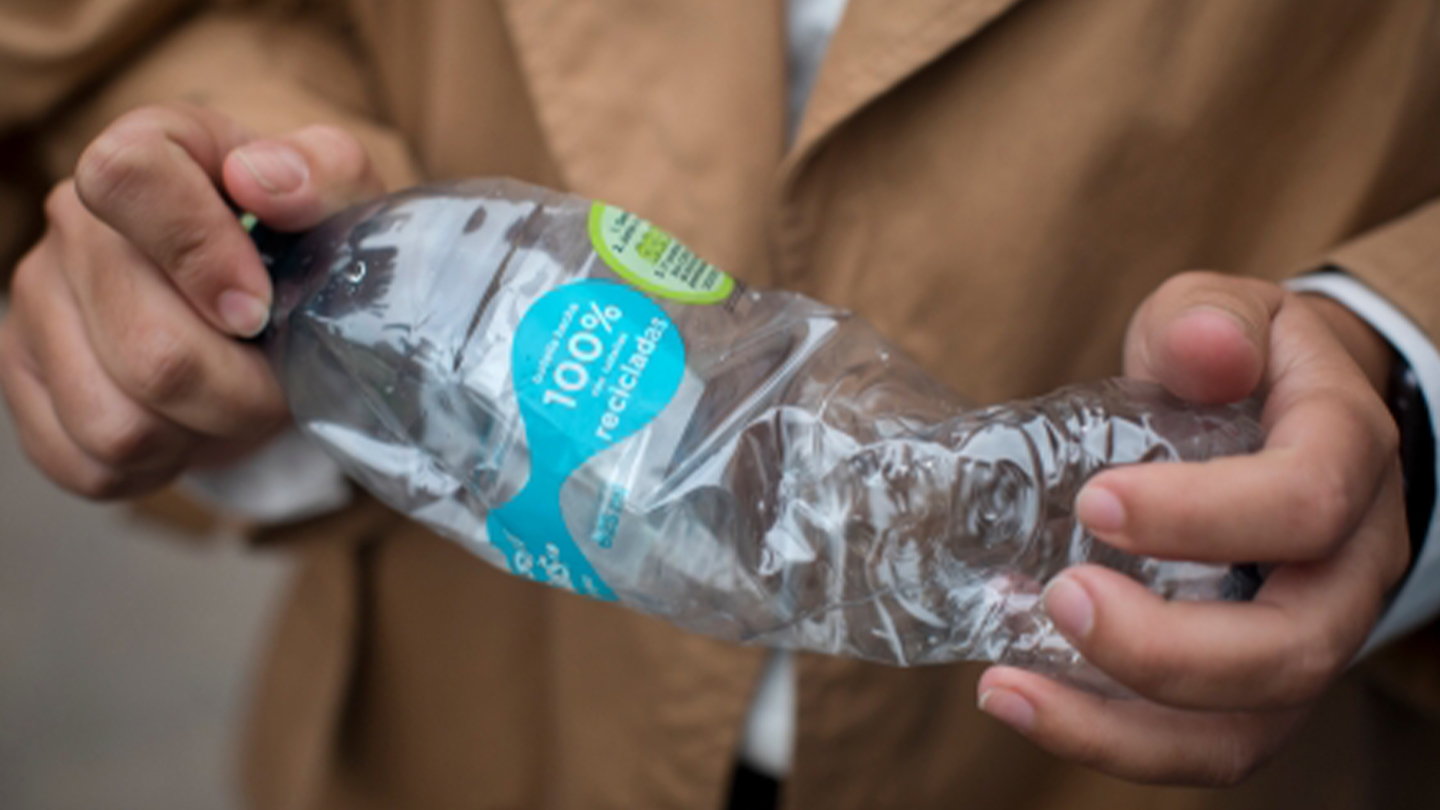 Unas manos aplastan una botella de plástico