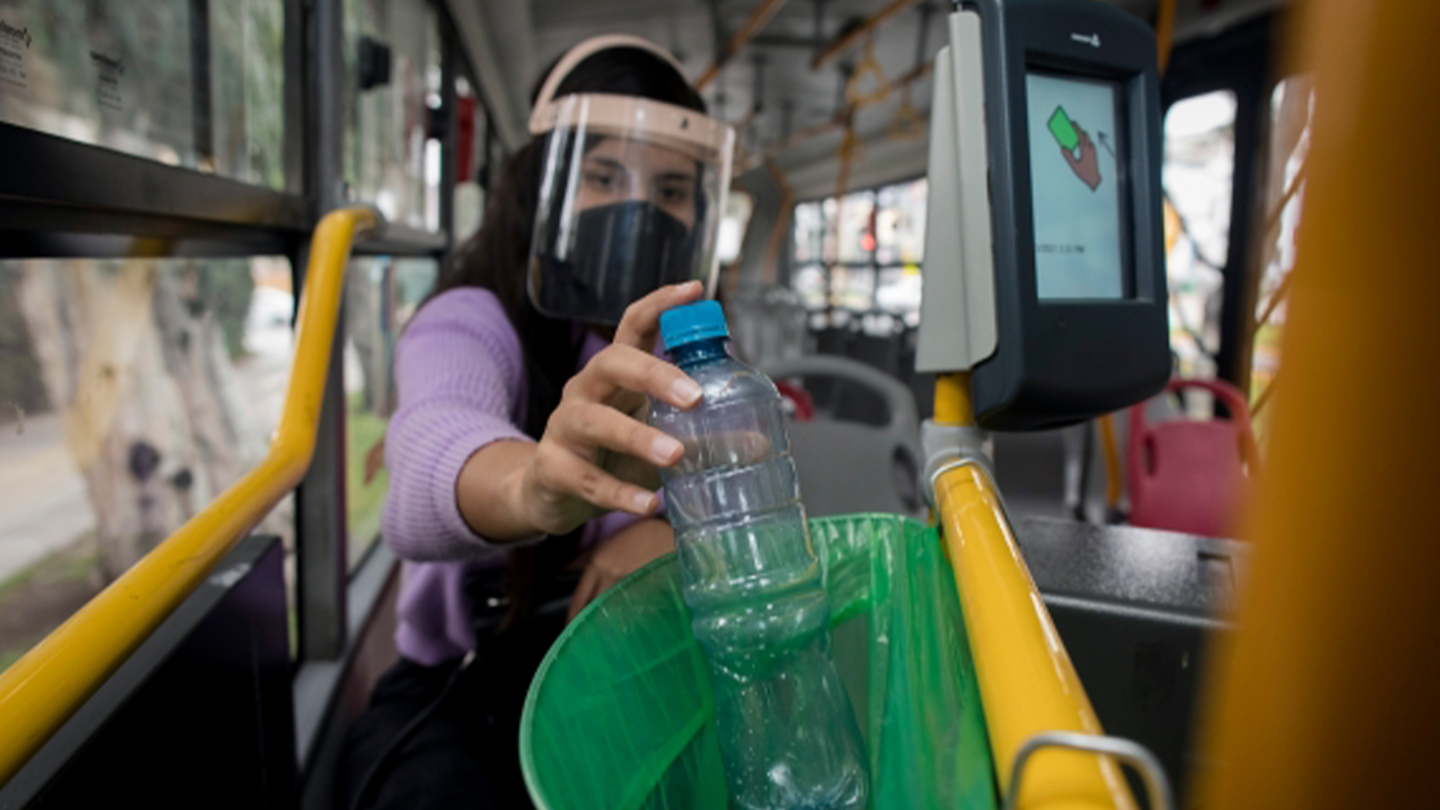 Mujer desechando botella de plástico en punto limpio de bus