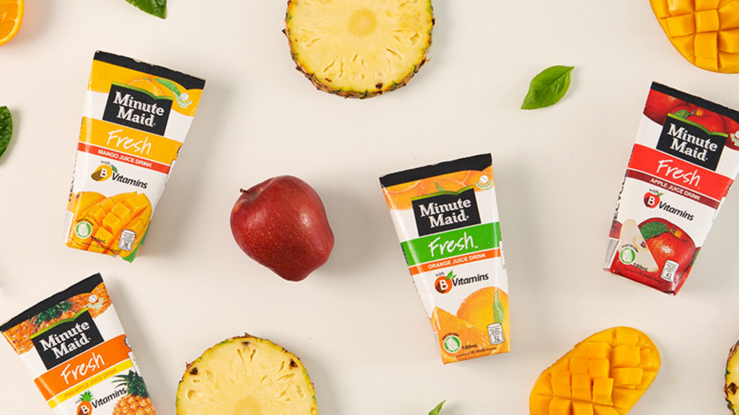 Top view of Minute Maid packaging in white background with apples, mango, orange and pineappleslices.