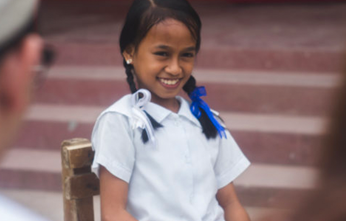Little girl with white t-shirt and blue bow smiling