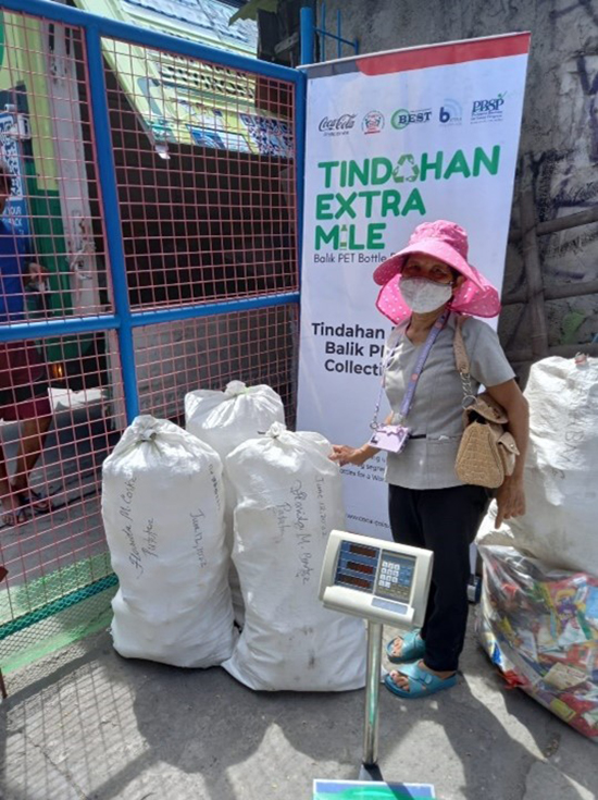  A woman posing next to three bags of plastic waste