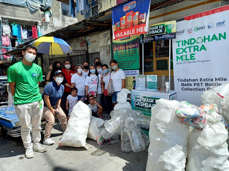 A group of people posing next to various bags of plastic waste