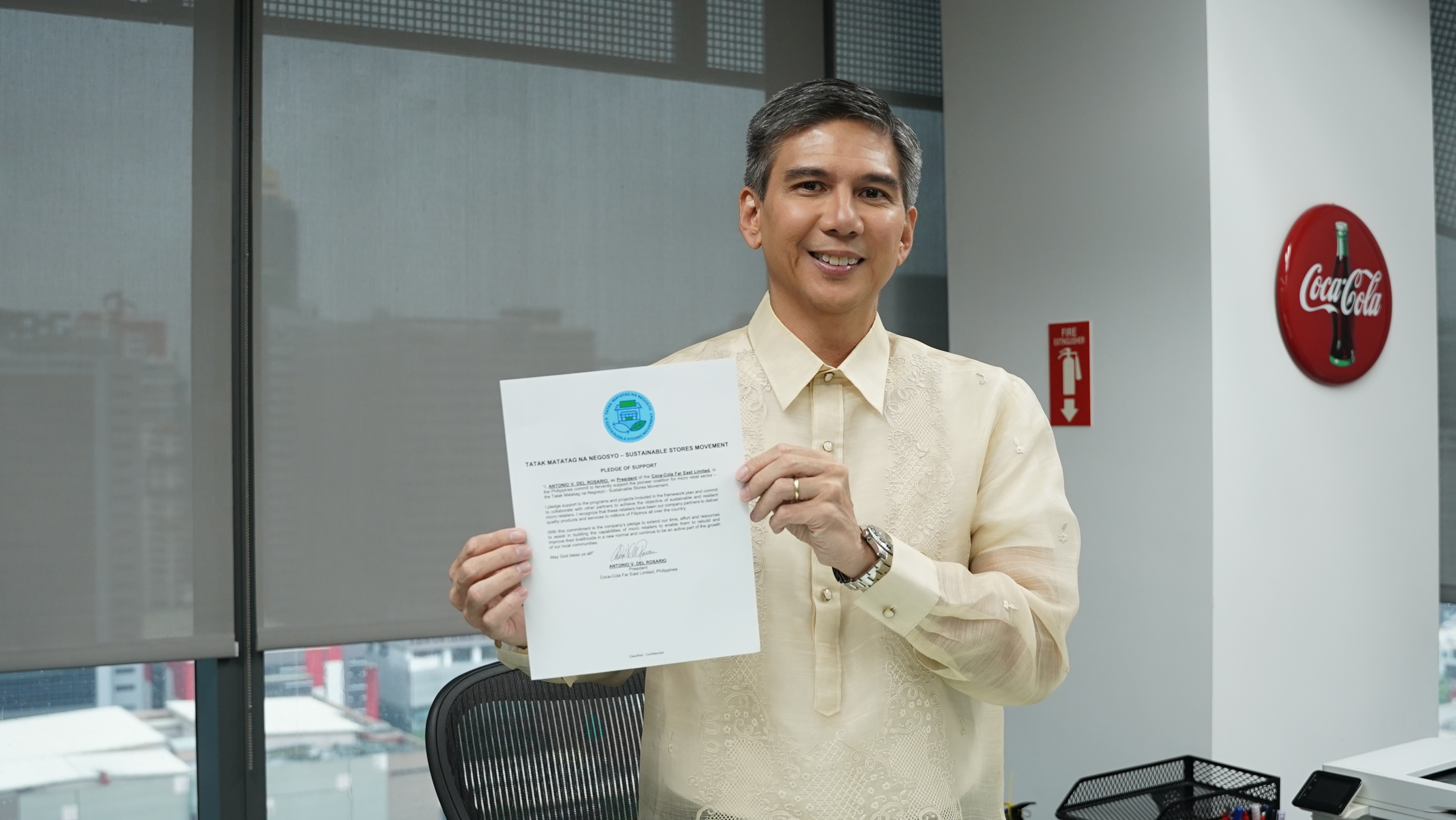 A man shows a Tatak Matatag na Negosyo Sustainable Stores Movement document inside a Coca-Cola office