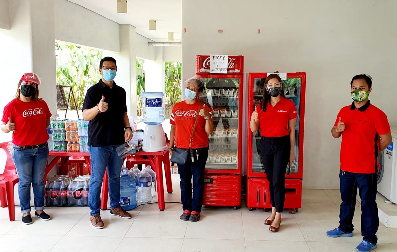 A group of five people in front of donated Coca-Cola products
