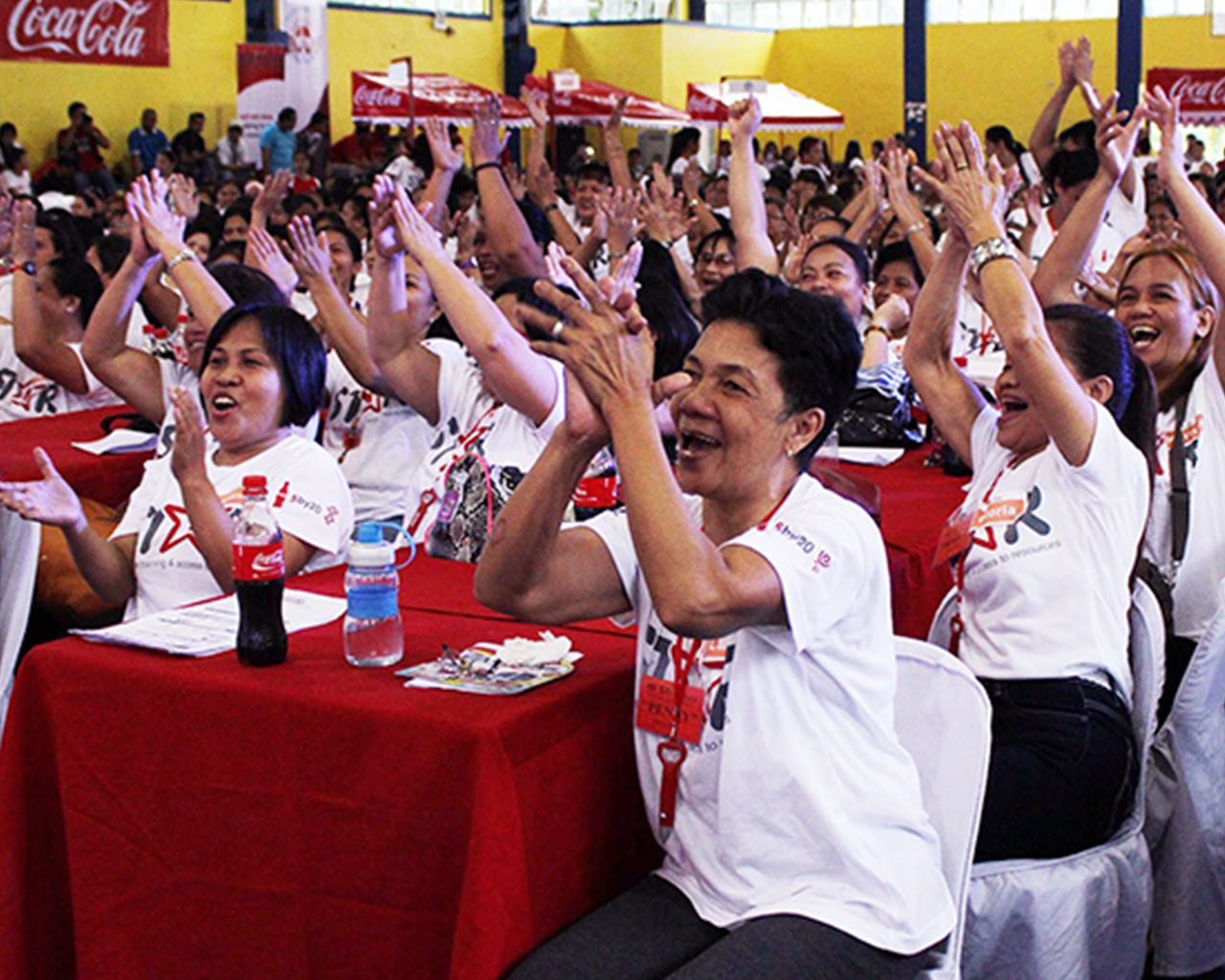 A audience of women applauding while sitting at tables