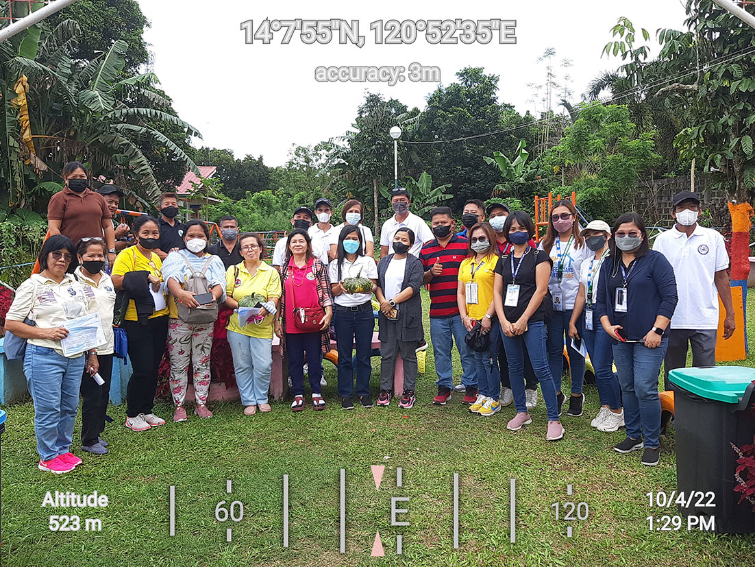 A large group of individuals wearing safety masks posing for a photograph on a backyard