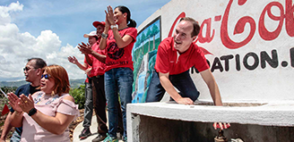 People clapping hands in front of a Coca-Cola Foundation mural