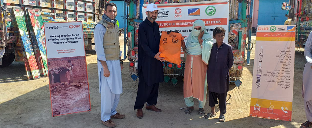A family holding a bag of supplies donated as part of the flood relief efforts in Pakistan made by The Coca-Cola Foundation and CARE
