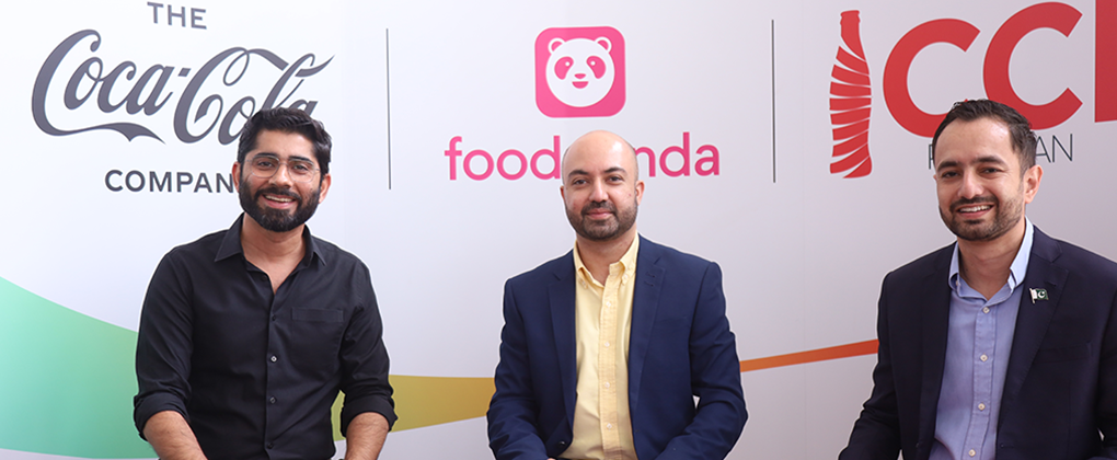 Three men in front of a banner with The Coca-Cola Company and Foodpanda logos