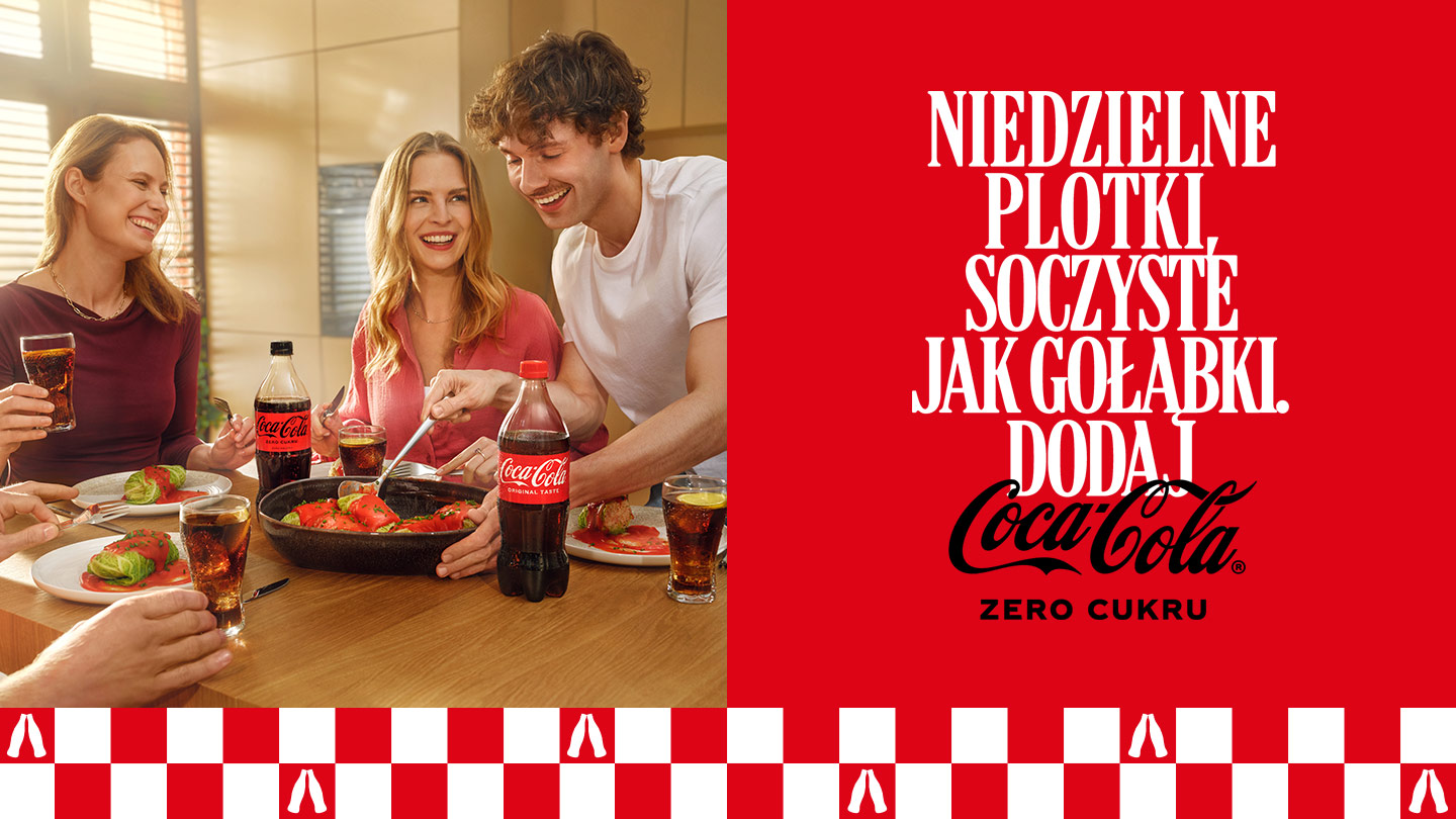 Trzy osoby przy stole z jedzeniem i butelkami Coca‑Coli, czerwony baner z hasłem reklamowym.